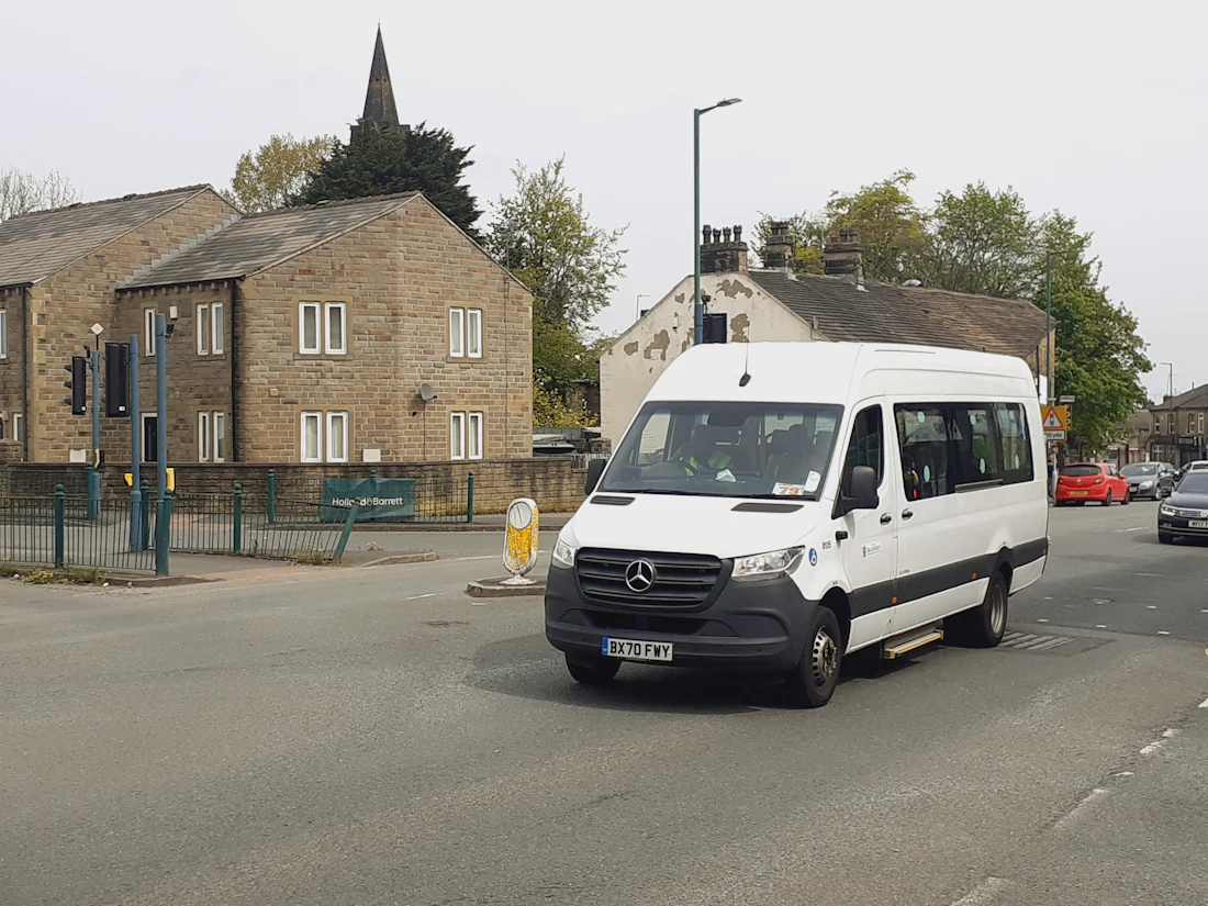 White passenger van driving through a downtown street