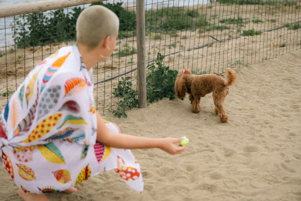 a little boy playing with a dog in the sand