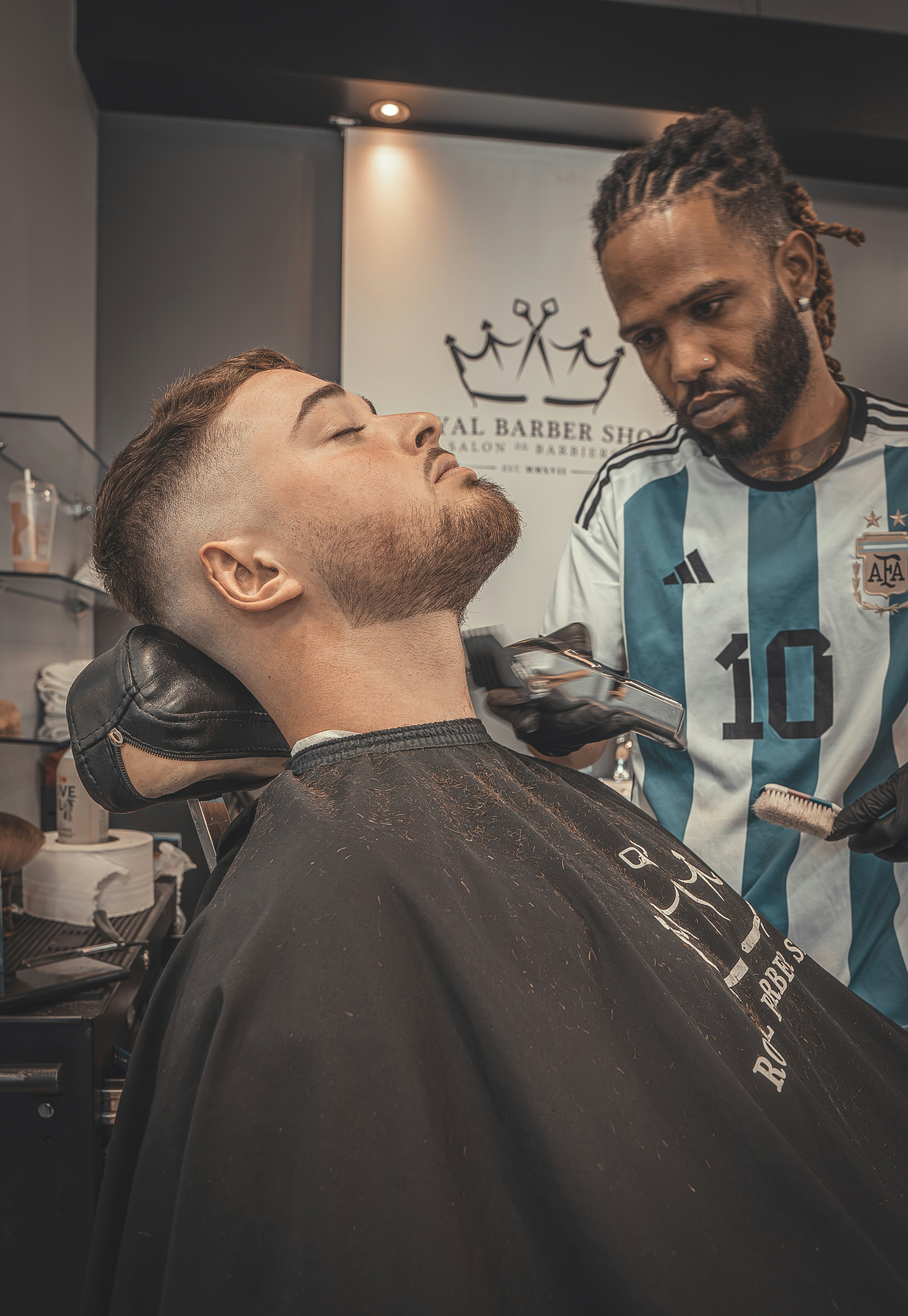 Barber trimming and shaping a full beard with clippers, man looking in mirror