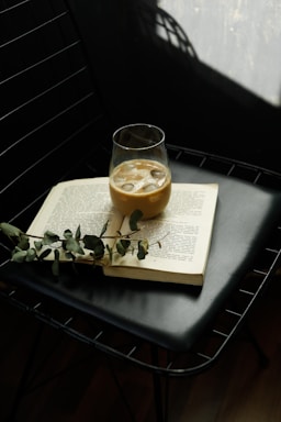 a glass of liquid sitting on top of an open book
