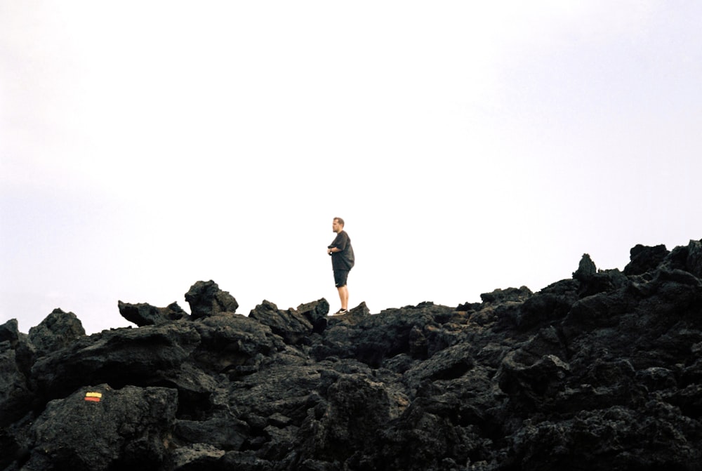 un uomo in piedi sulla cima di una collina rocciosa