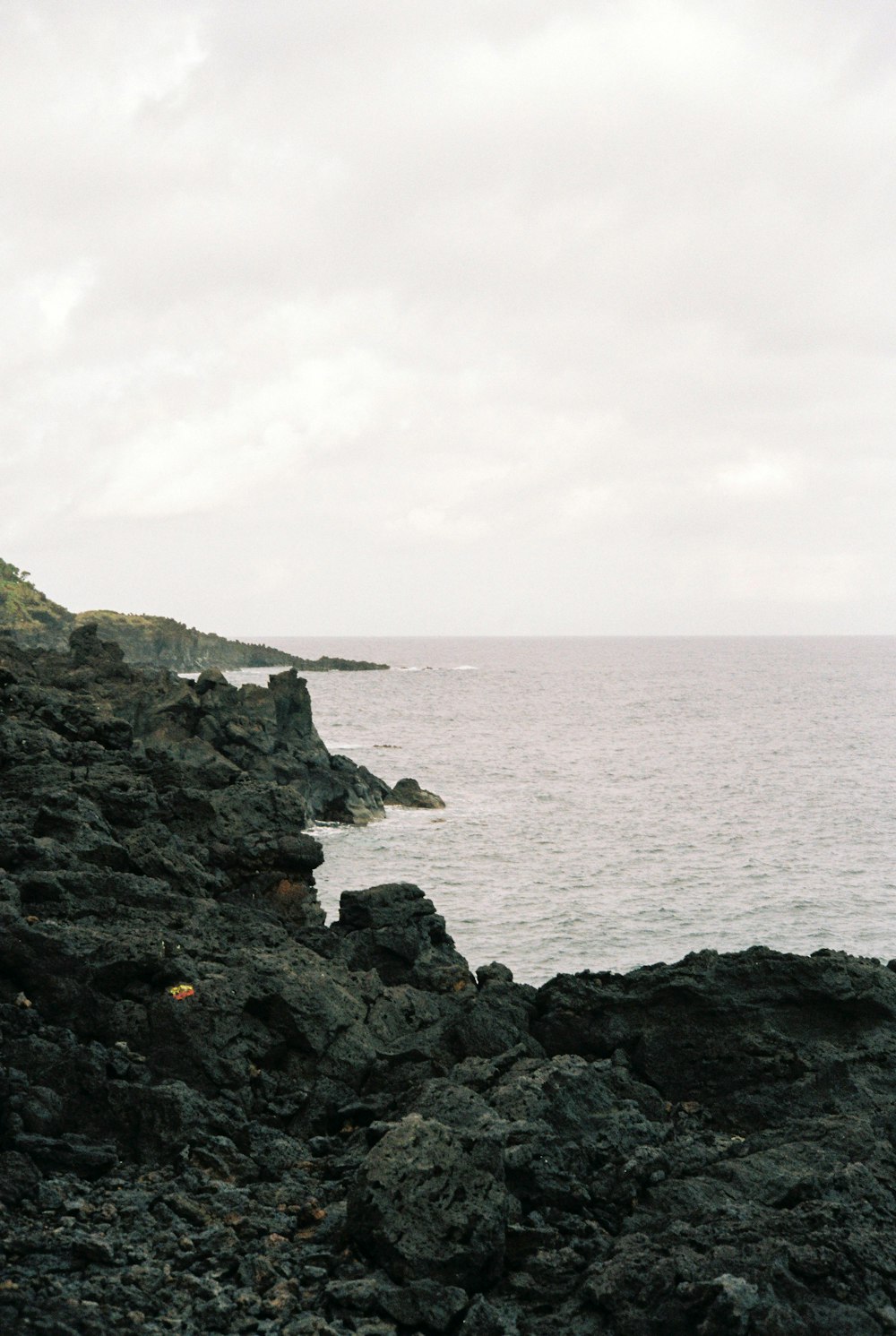 a man standing on a rocky cliff next to the ocean