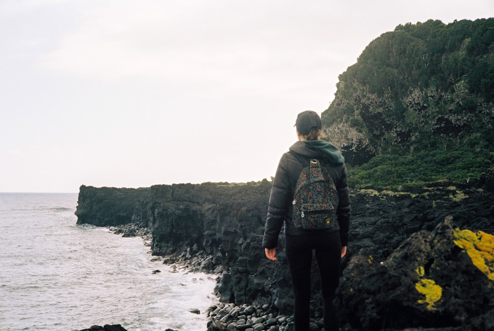 um homem em pé em um penhasco com vista para o oceano