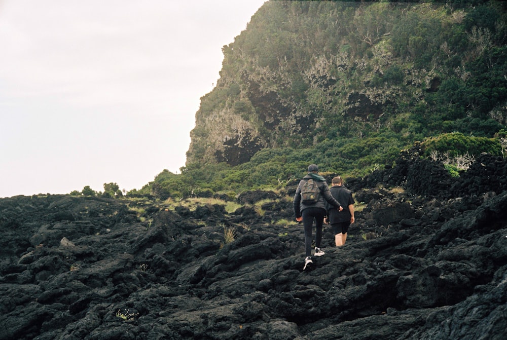 a couple of people walking up a rocky hill