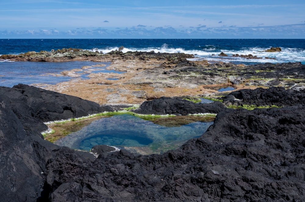 Un cuerpo de agua rodeado de rocas cerca del océano
