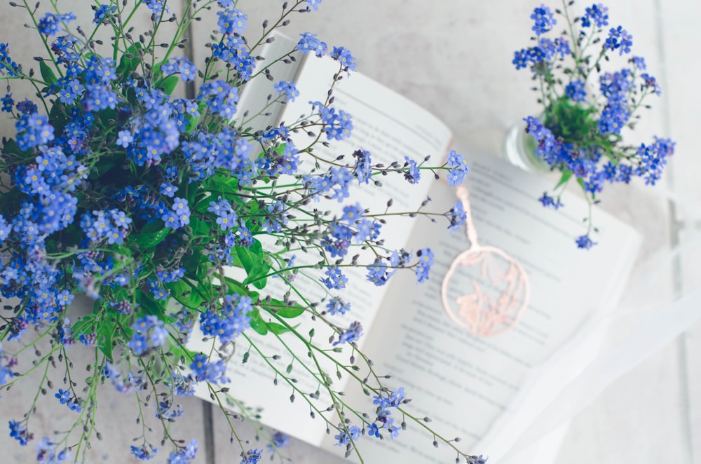 a bouquet of blue flowers sitting next to an open book