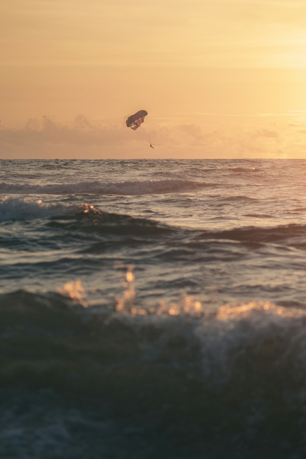 a kite flying over the ocean at sunset