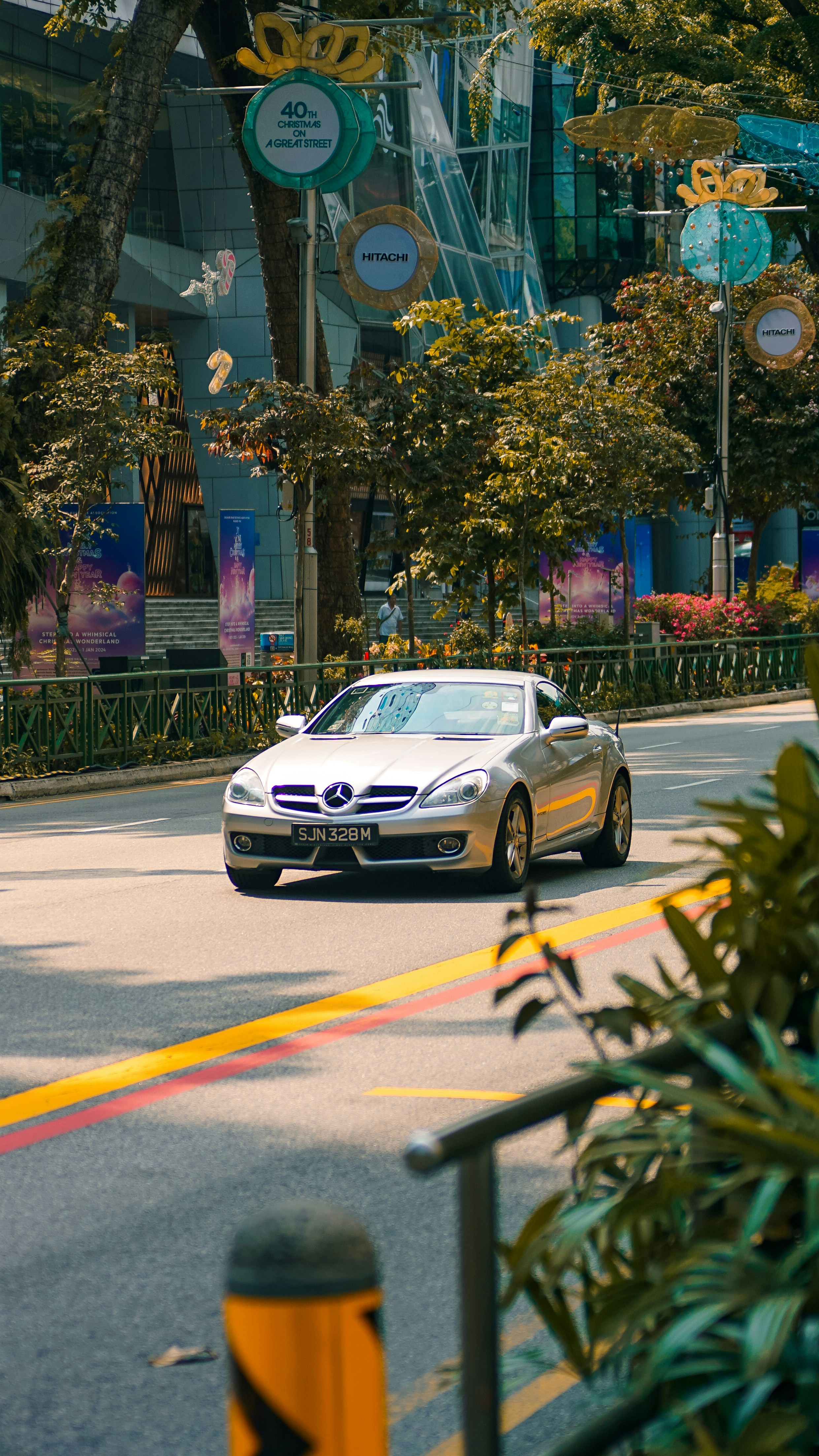 a silver car driving down a street next to a tall building