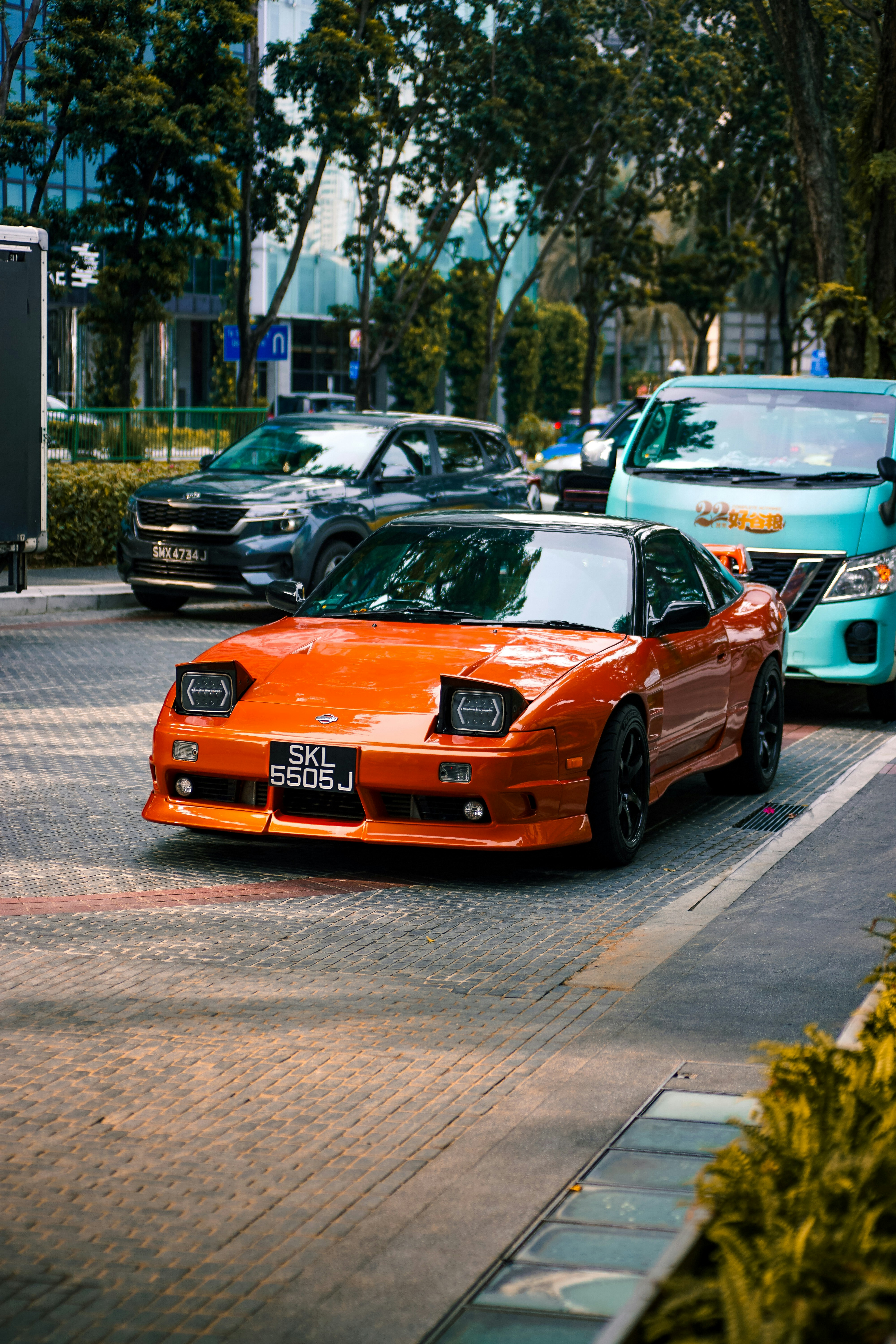 an orange sports car driving down a city street