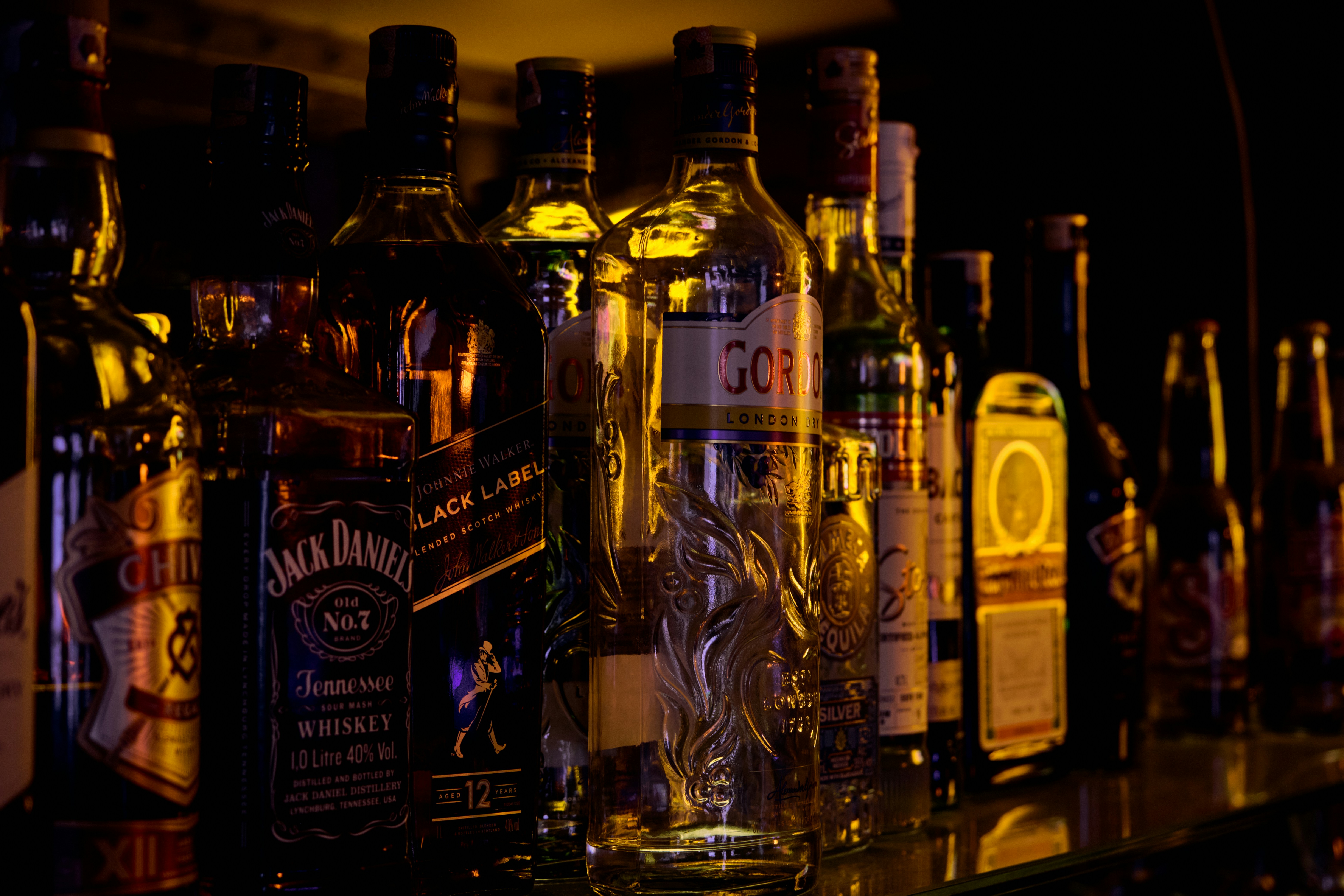 a row of liquor bottles sitting on top of a bar, 
