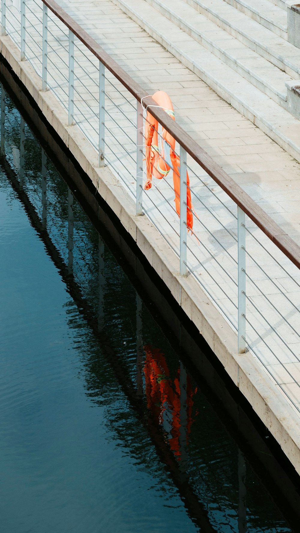 an orange flag is hanging on a railing over a body of water