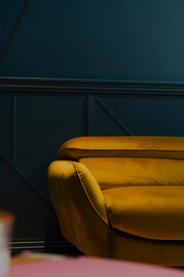 a yellow couch sitting in a living room next to a pink table