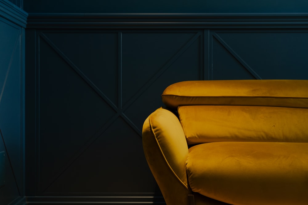 a yellow couch sitting in a room next to a wall