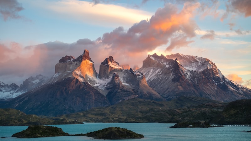 Granite horns of the Paine massif lit pink at sunrise above a turquoise lake dotted with small islands