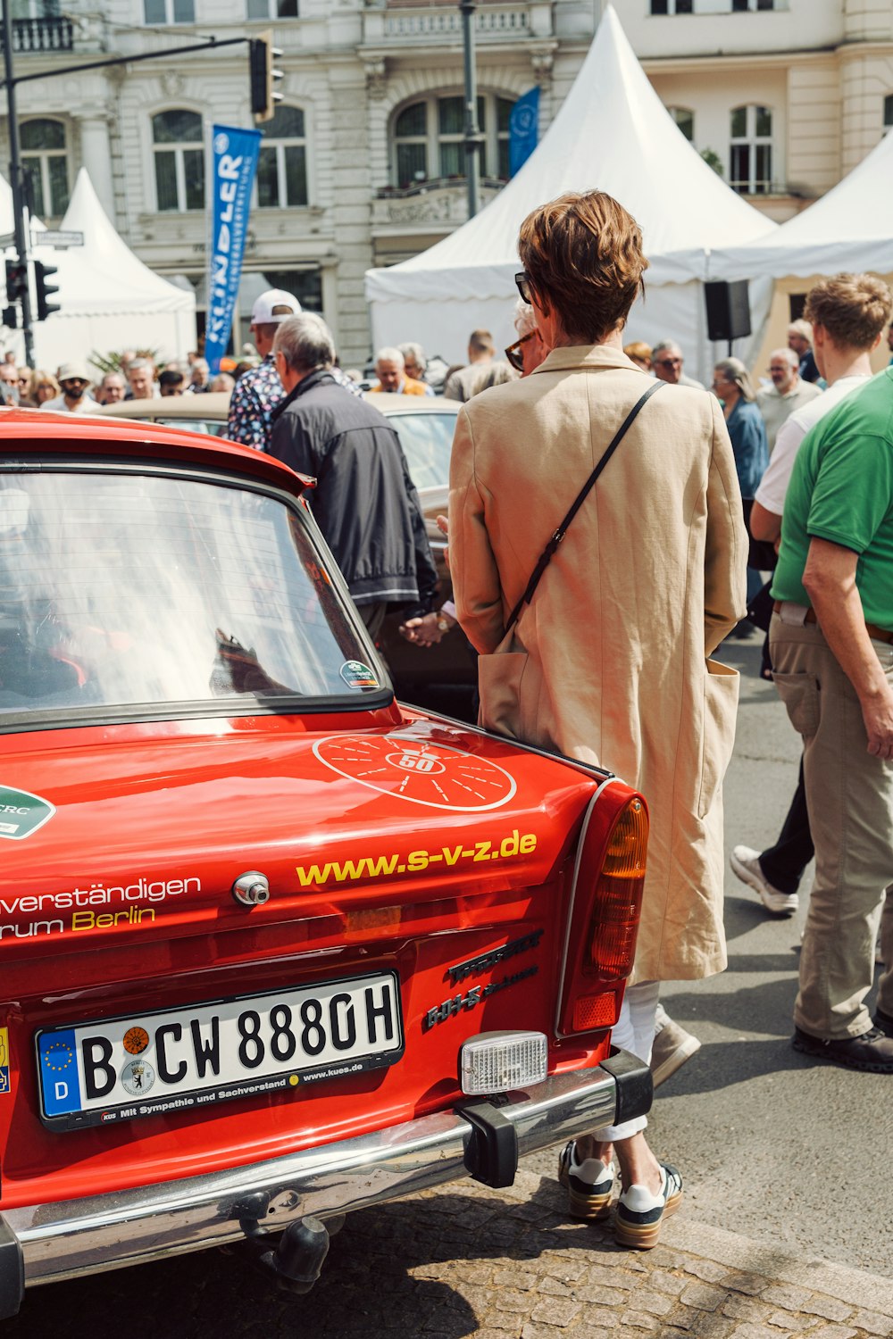 a red car parked in front of a crowd of people