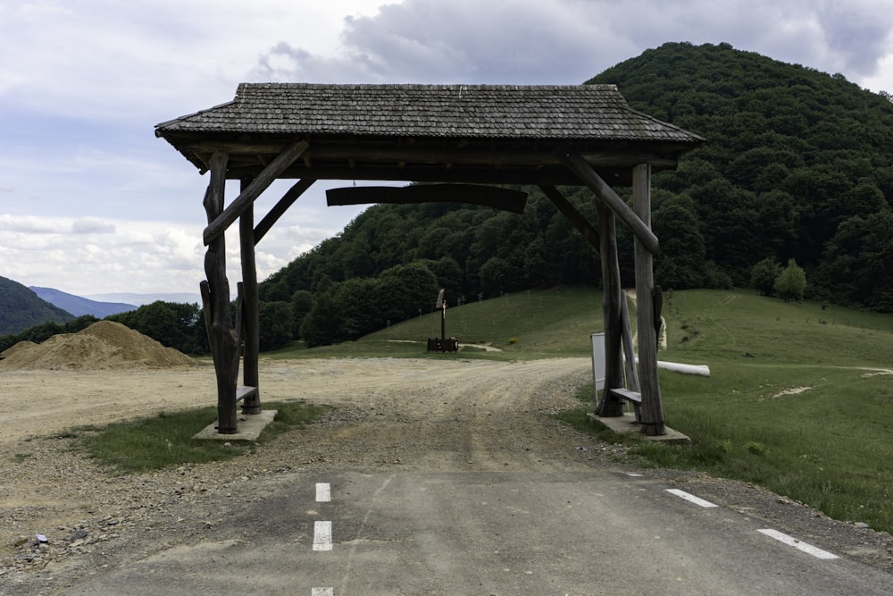 a wooden shelter sitting on the side of a dirt road