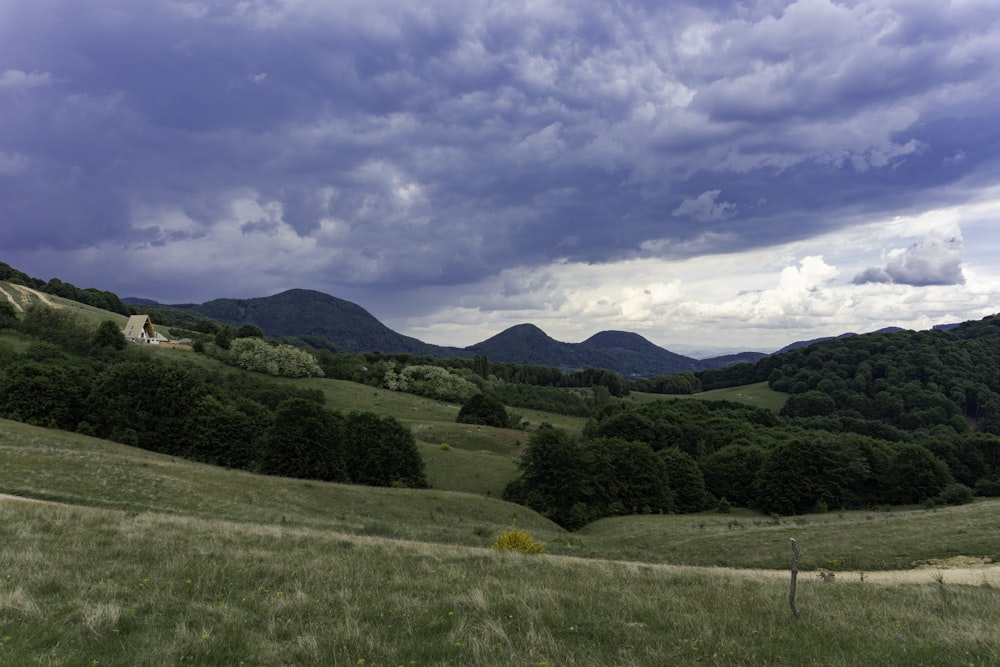 a field with mountains in the background under a cloudy sky
