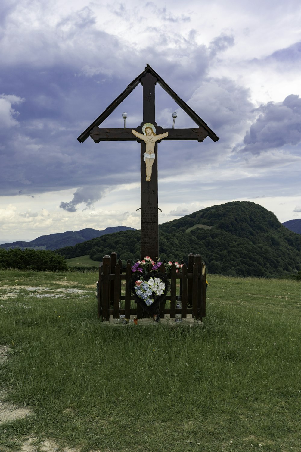 a wooden cross with a wreath of flowers in front of it