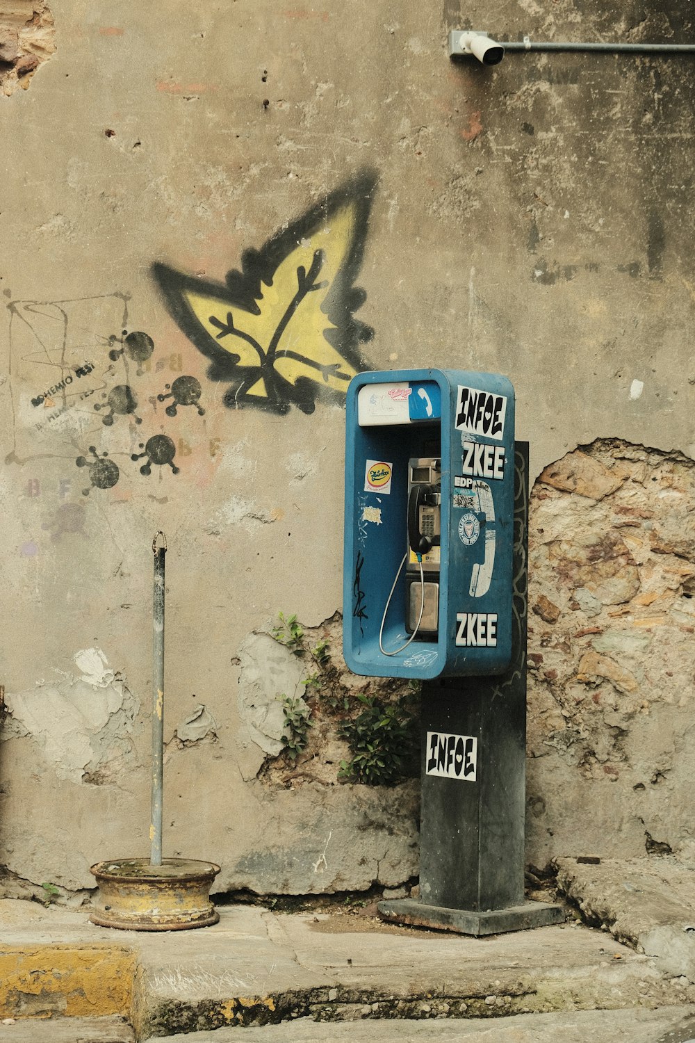 un téléphone bleu posé à côté d’un mur avec des graffitis dessus