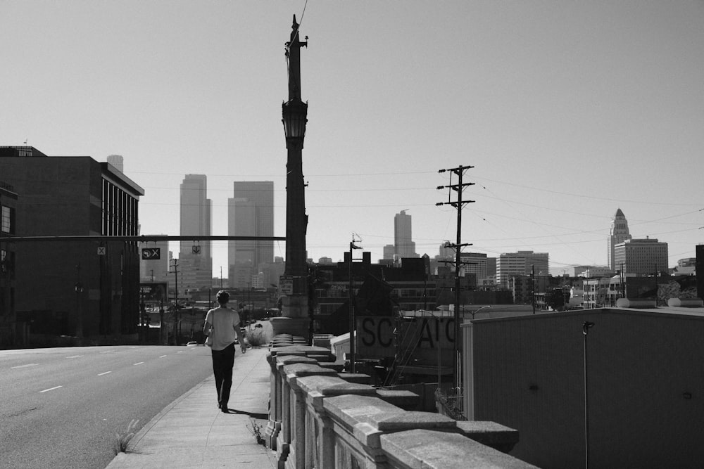 a man walking down a sidewalk next to a tall building