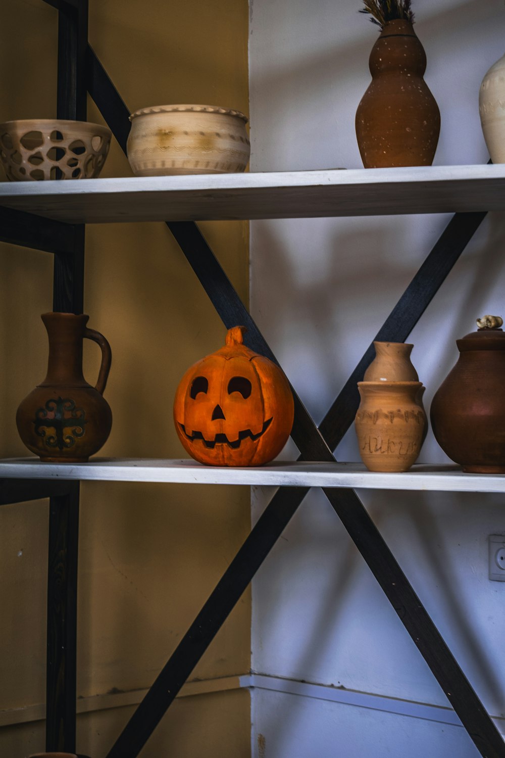 a shelf filled with vases and a carved pumpkin