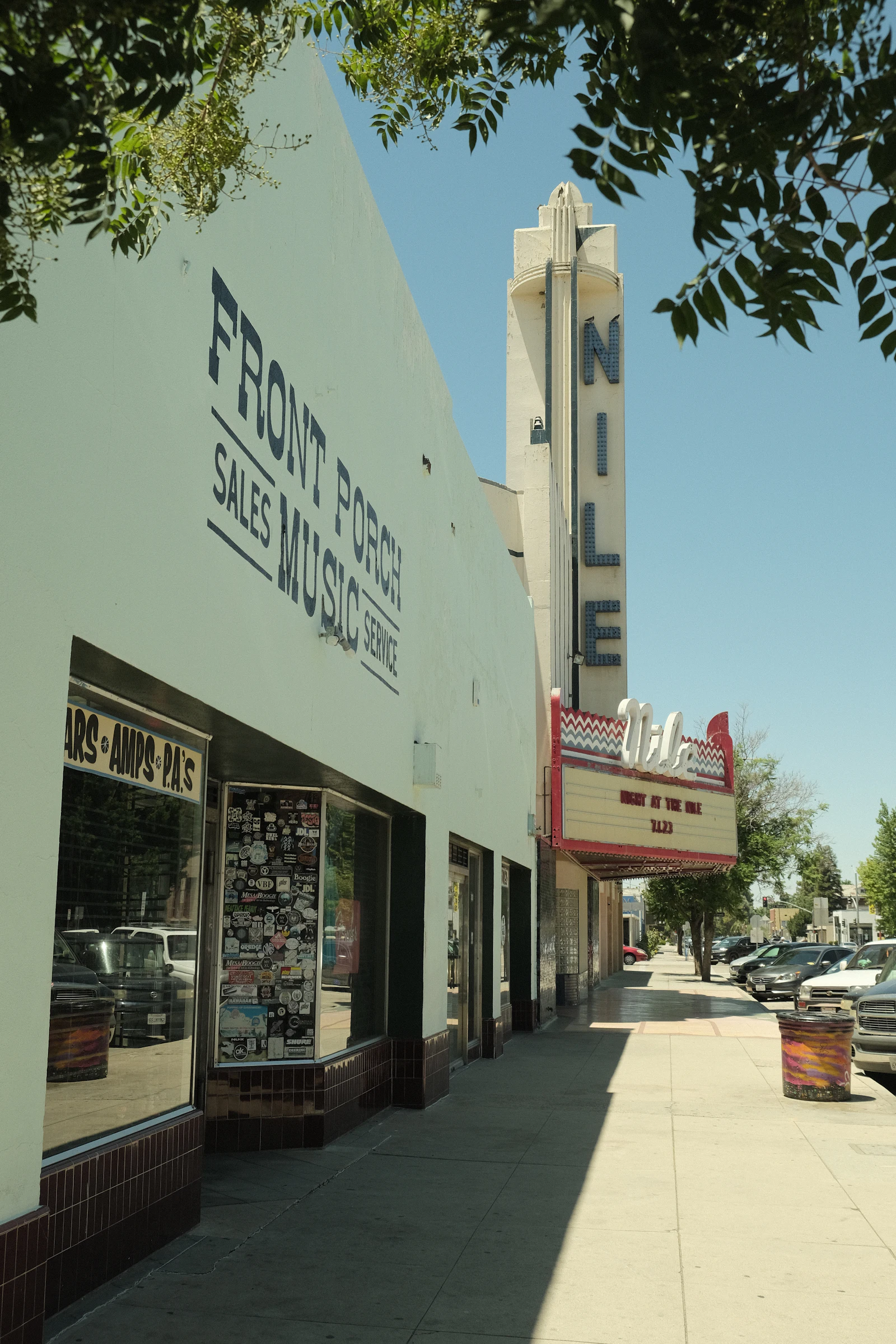 An old movie theater front with cars parked along the curb.
