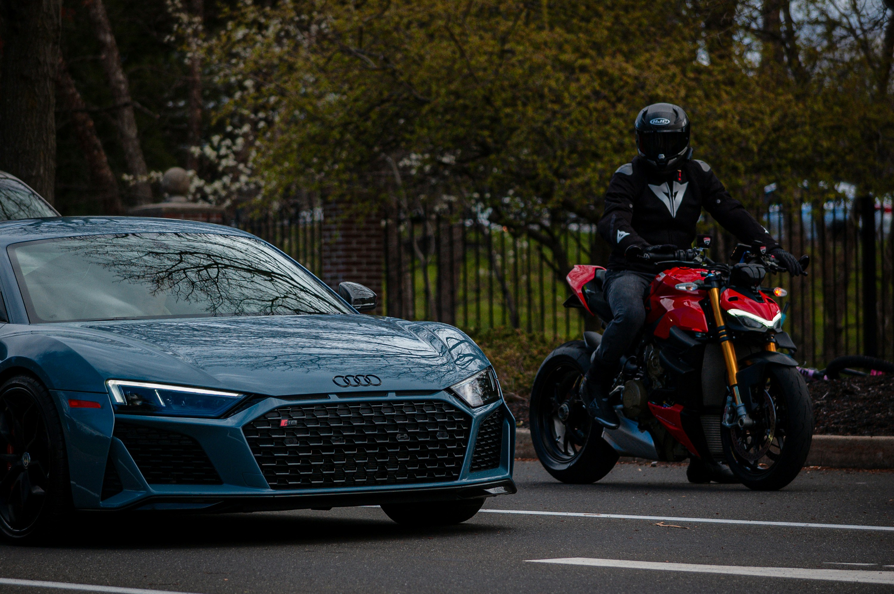 a man riding a motorcycle next to a blue sports car
