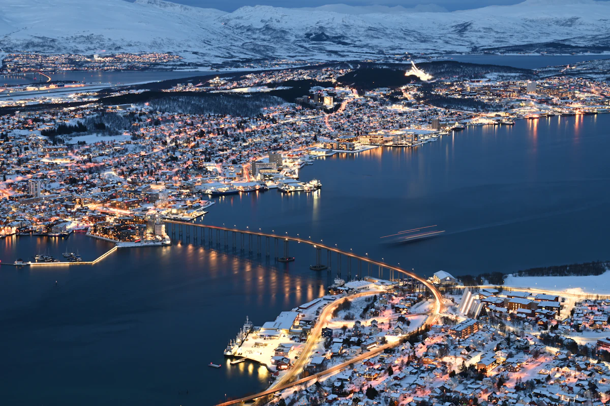 La ville de Tromsø illuminée la nuit, entre fjord et montagnes