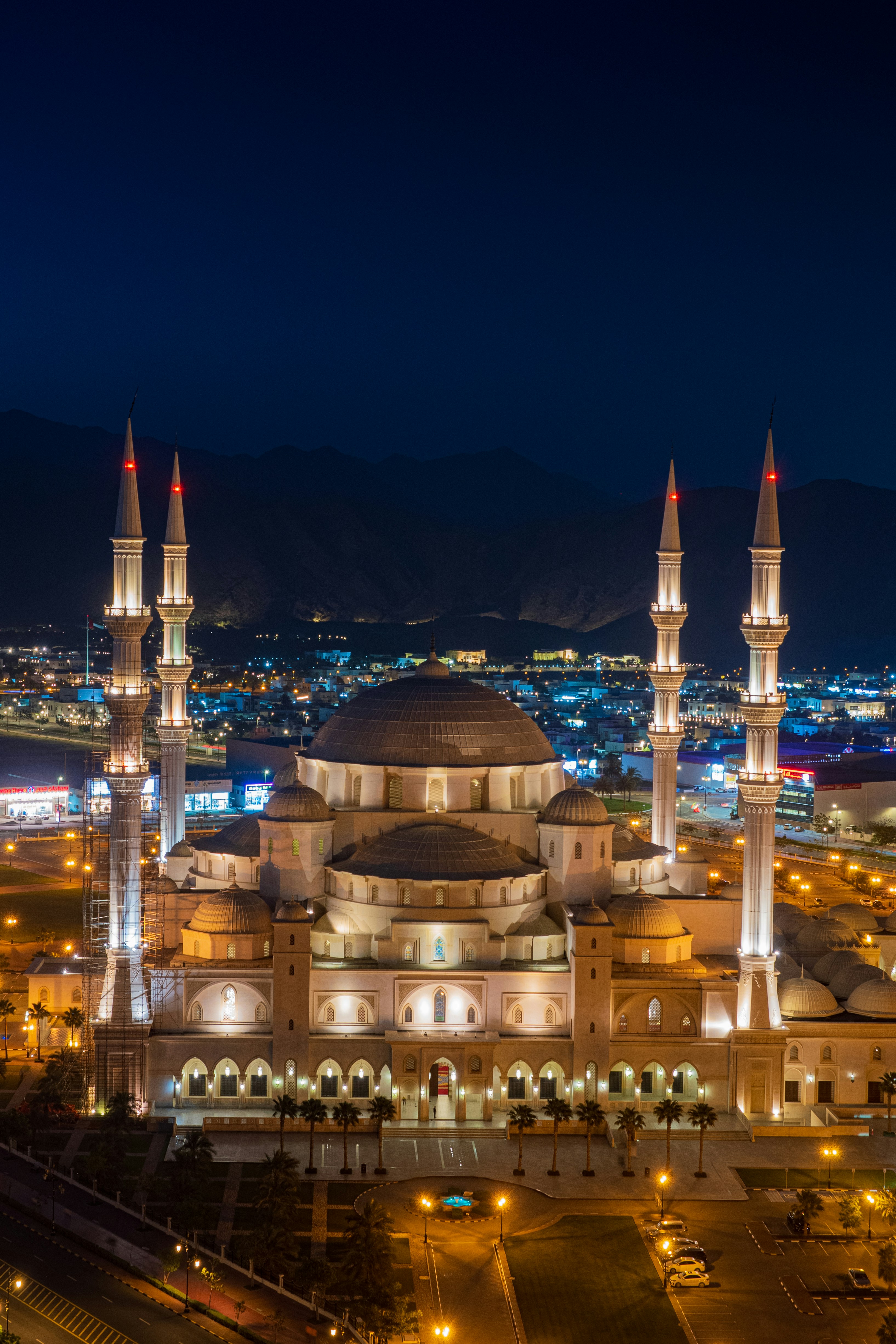 Makkah grand mosque at night with bright minarets, dark sky, golden illumination reflecting on marble