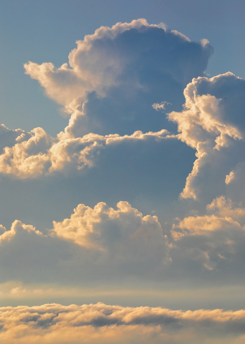 a plane flying through a cloudy blue sky