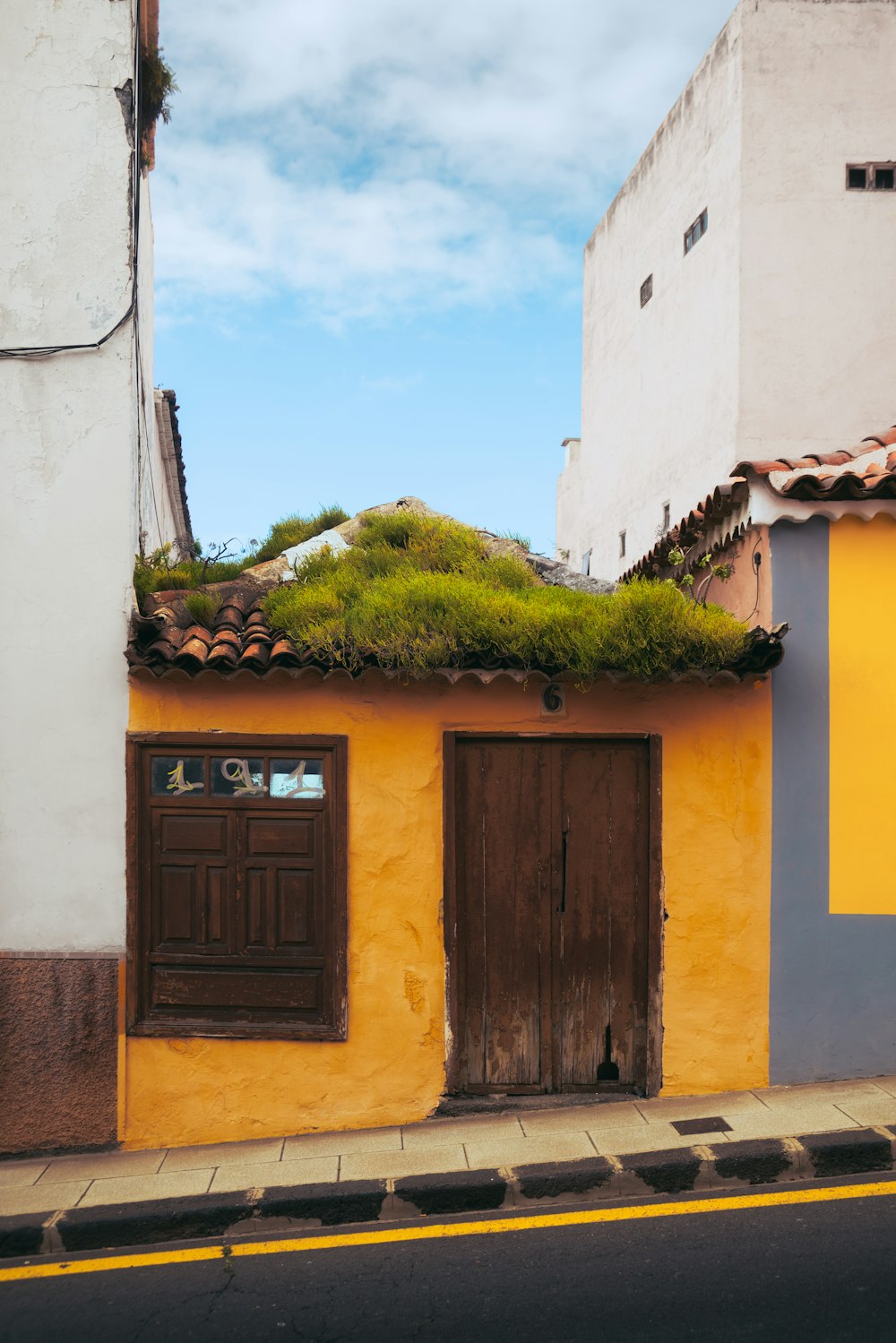 a yellow building with a green roof and two brown doors