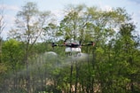 a small plane flying over a forest filled with trees