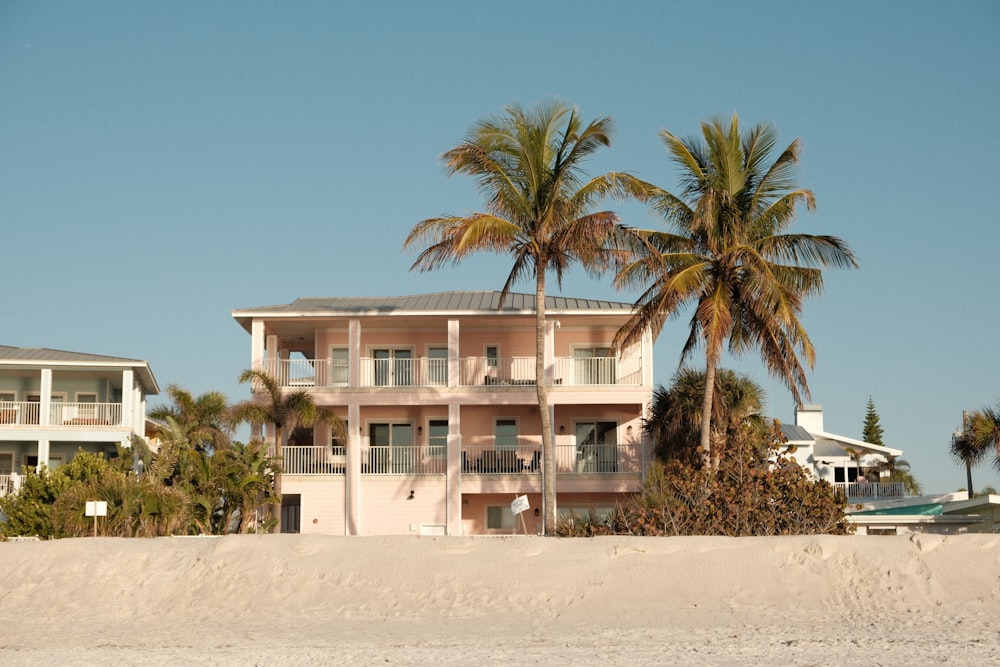 a pink house on the beach with palm trees