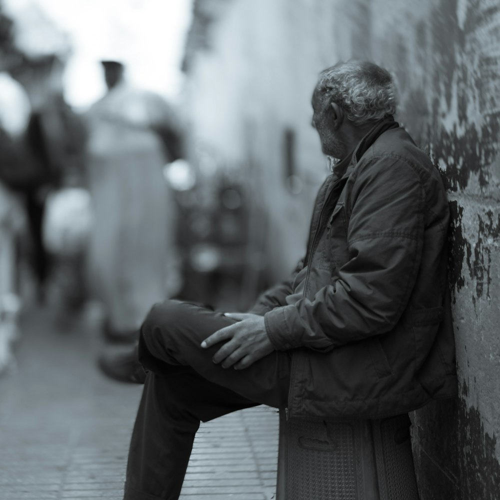 a man sitting on a bench next to a wall