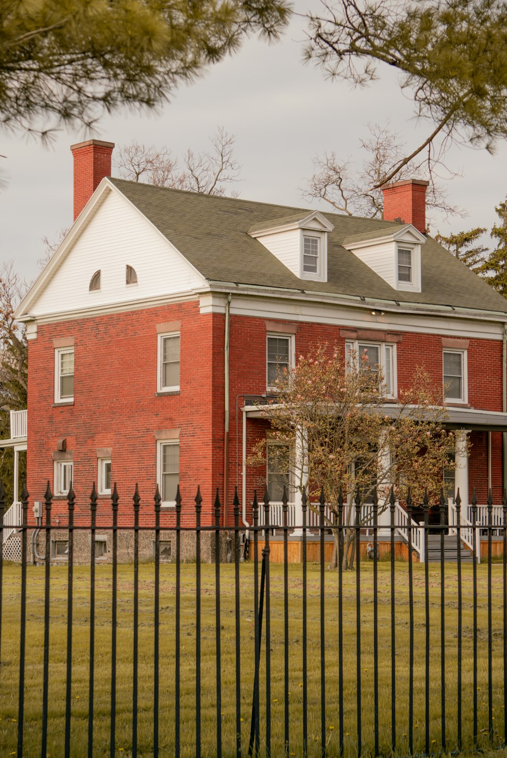 a large red brick house behind a black fence