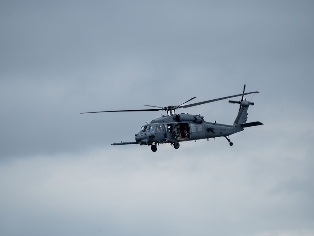 un hélicoptère militaire volant dans un ciel nuageux