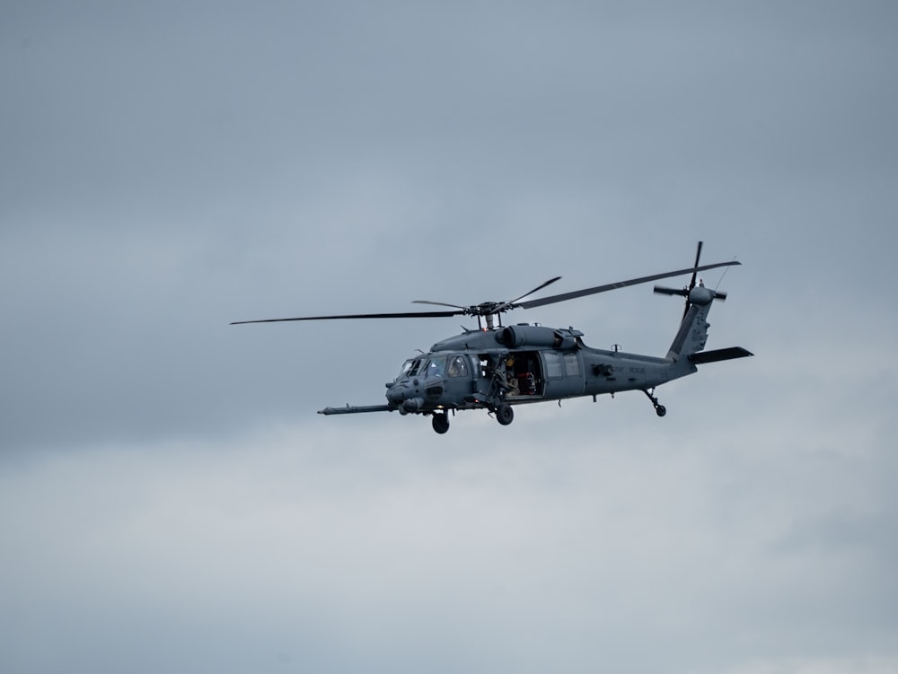 a military helicopter flying through a cloudy sky