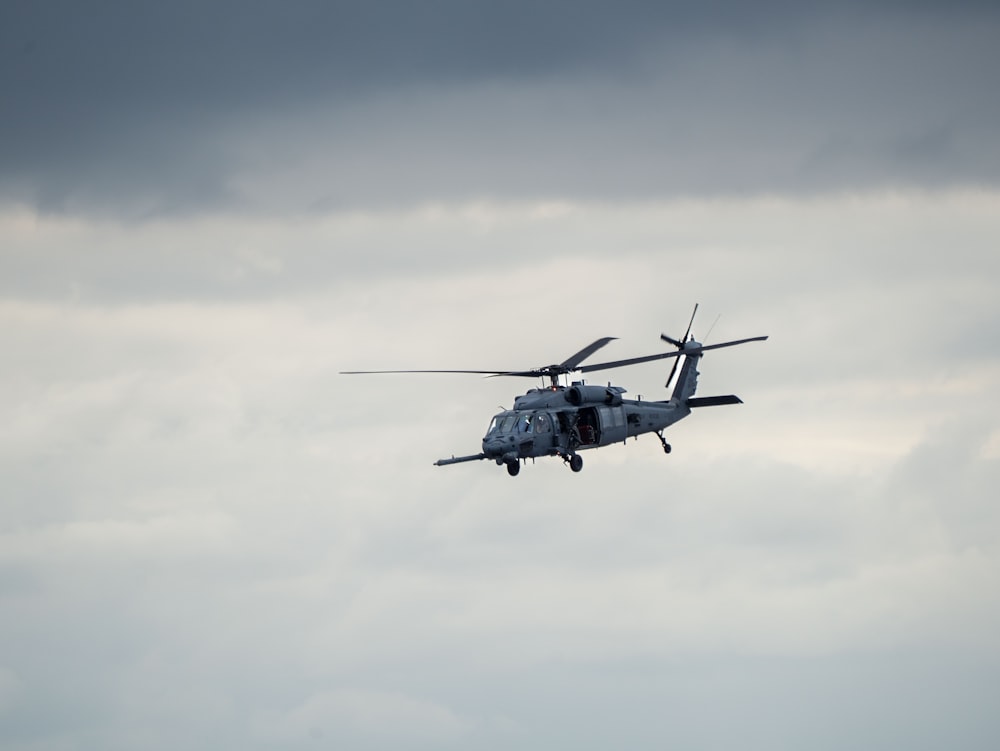 a helicopter flying in the sky on a cloudy day