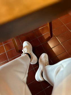 a pair of white shoes sitting on top of a tiled floor