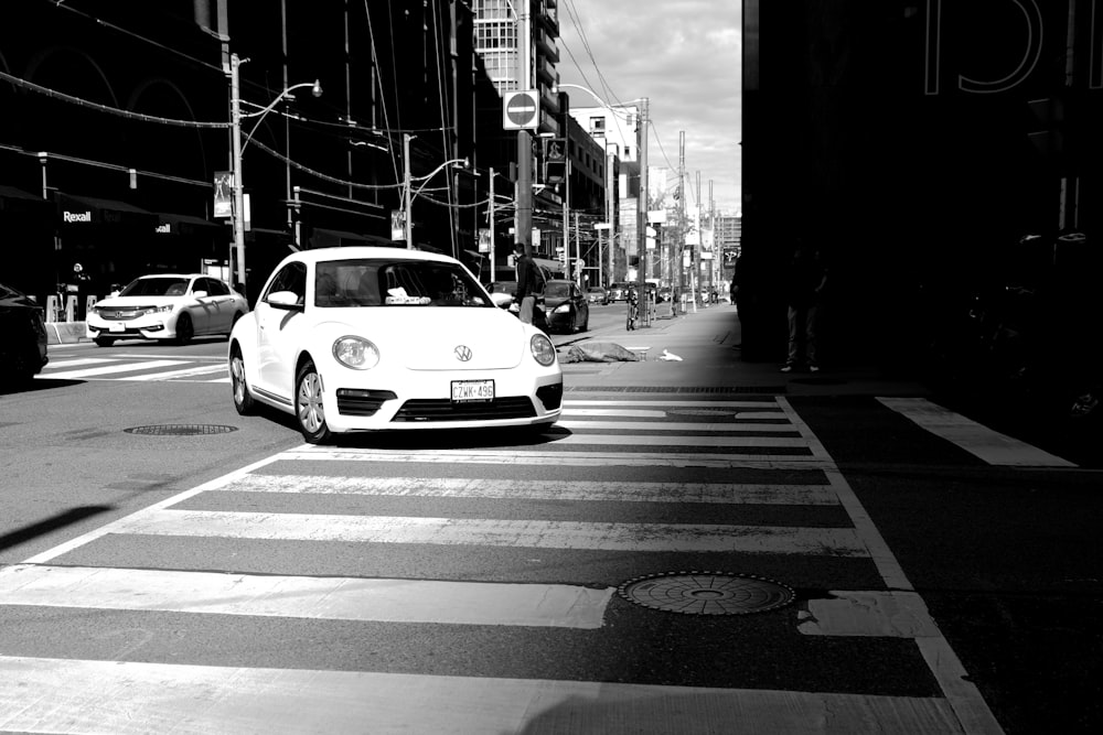 a white car driving down a street next to tall buildings