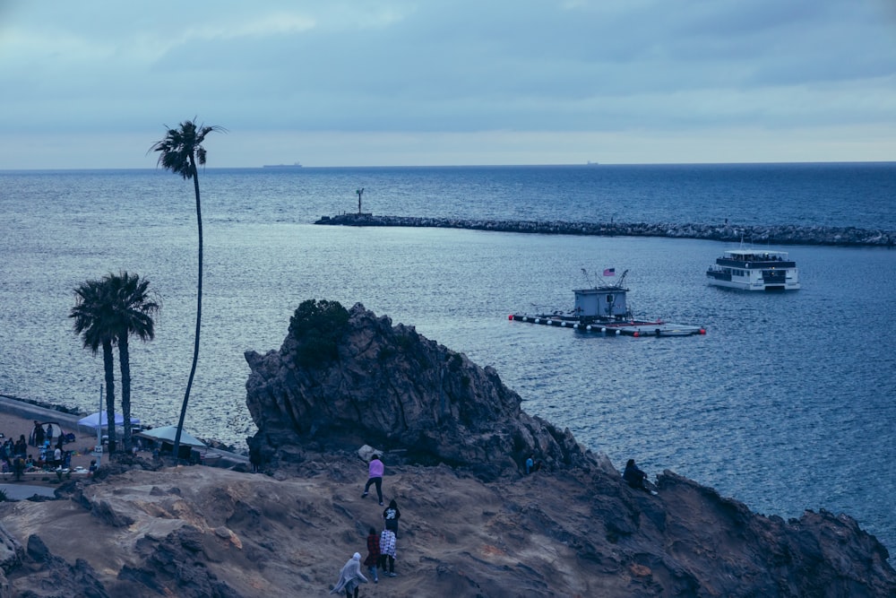 a group of people standing on top of a cliff next to the ocean