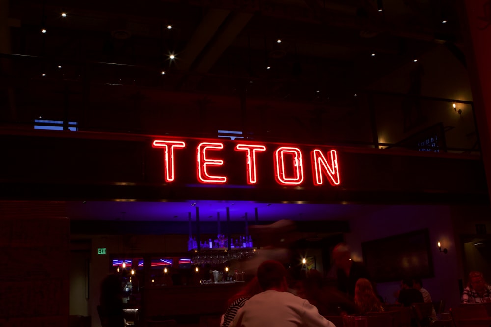 a neon sign that reads teton above a bar