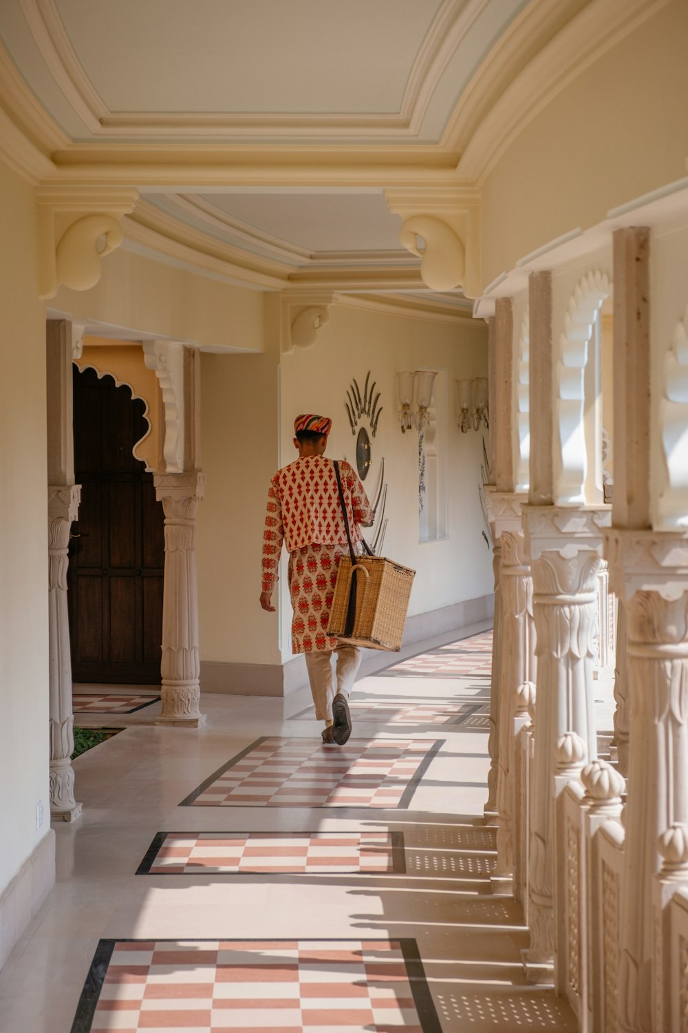 a man walking down a hallway carrying a basket