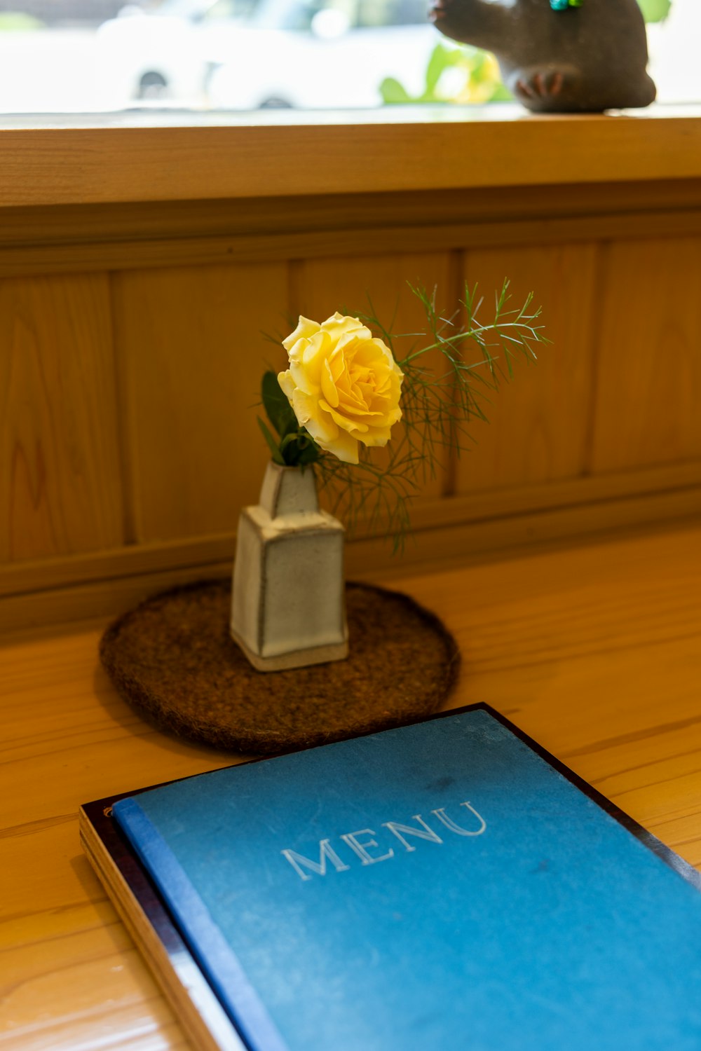 a small vase with a yellow rose on a table