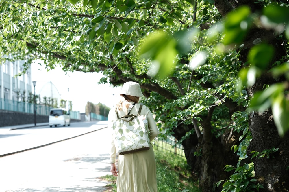 a woman in a white hat is walking down the street