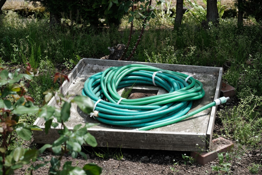 a bunch of green hoses sitting on top of a wooden box