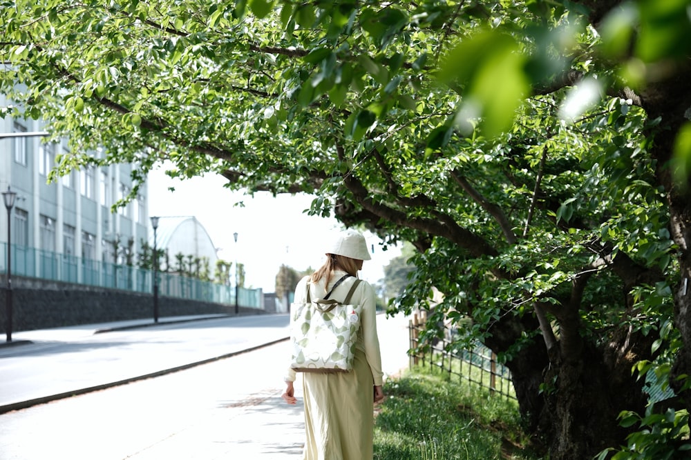 a man walking down a sidewalk next to a tree