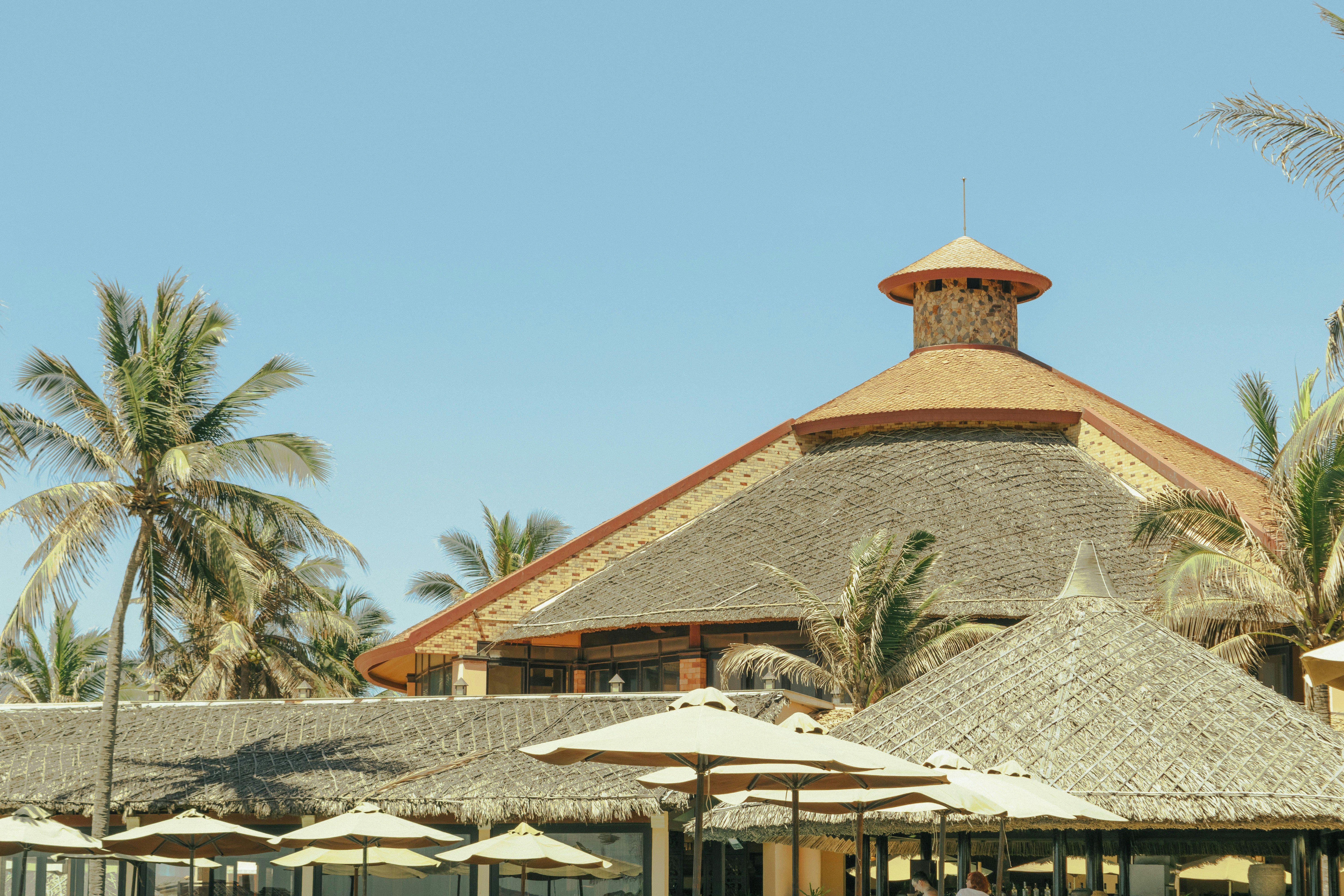 a building with a thatched roof surrounded by palm trees