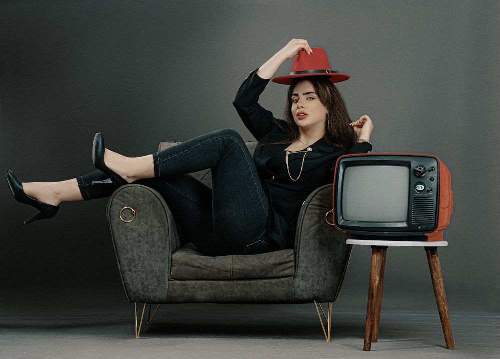 a woman sitting on a chair with a red hat on her head