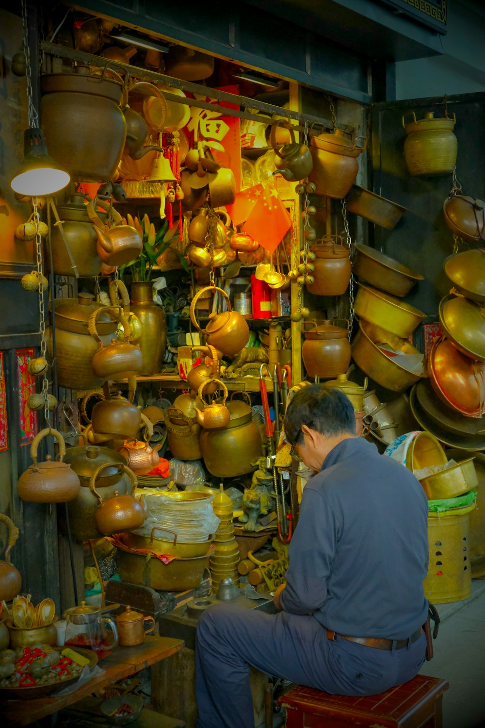 a man sitting on a stool in a room filled with pots and pans